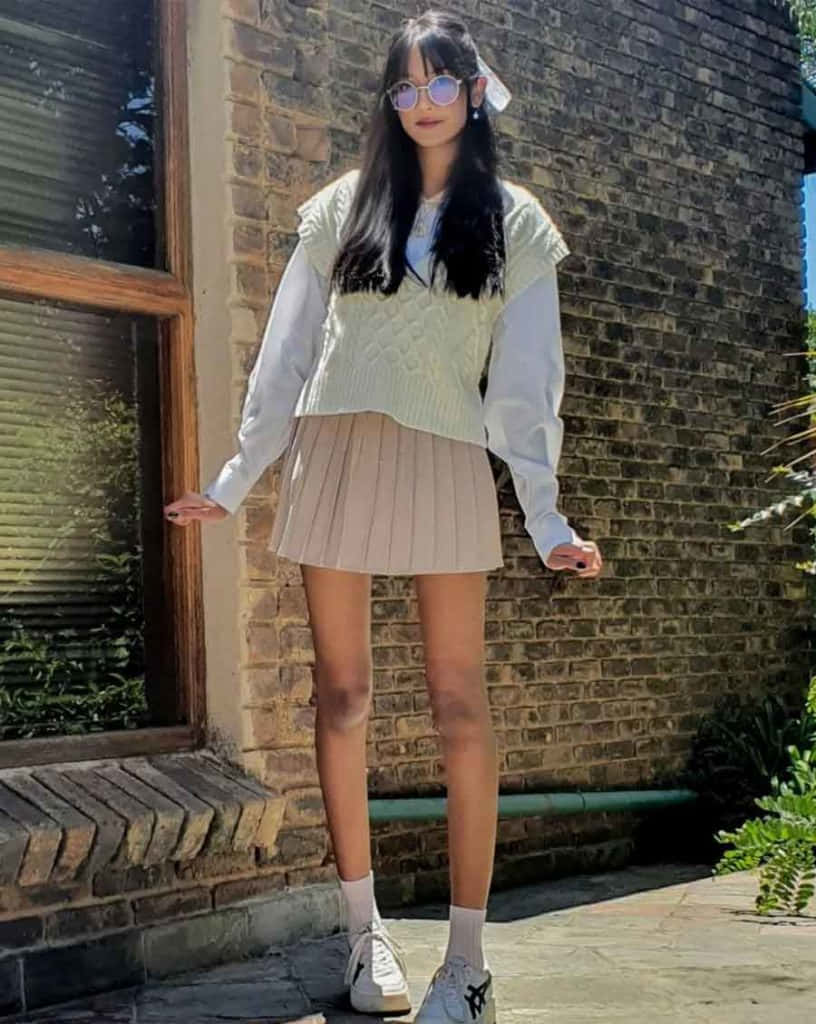 Download A Girl Wearing A White Sweater And A Pleated Skirt | Wallpapers.Com