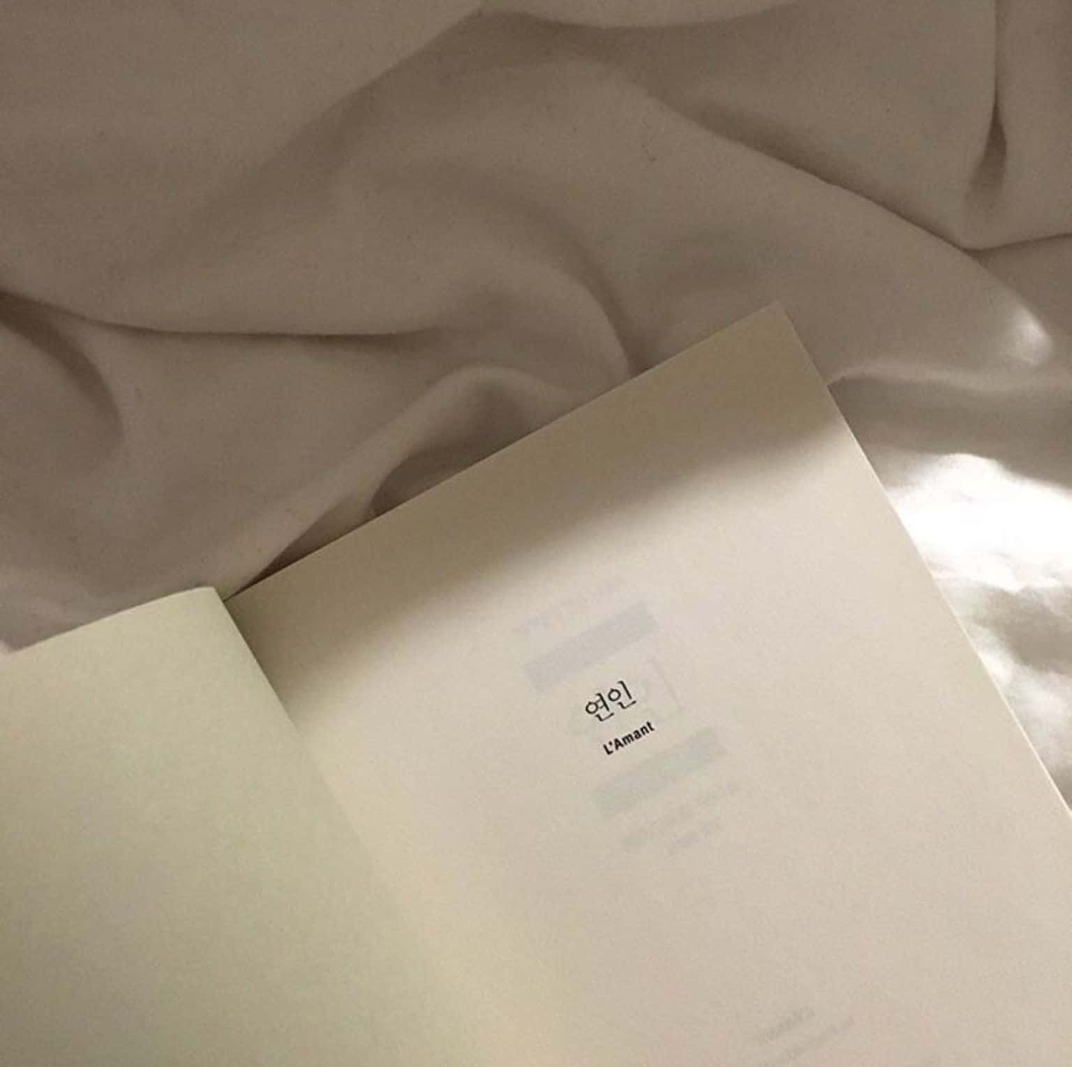 A Book With A White Cover On A Bed