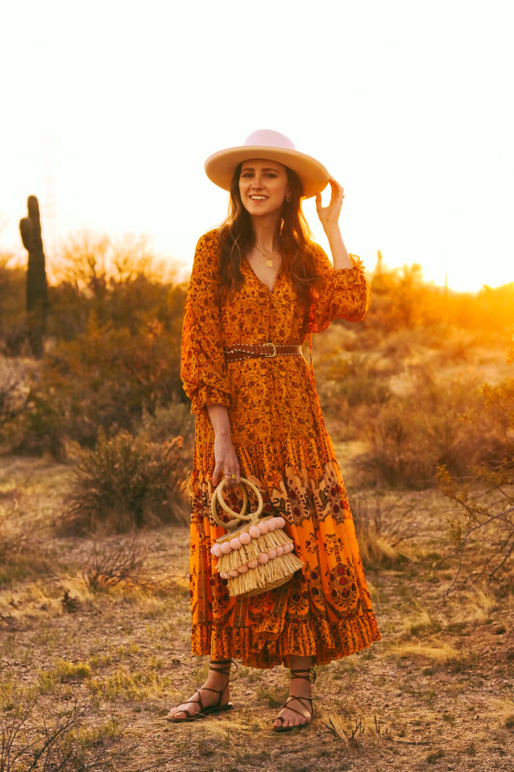 A Woman In An Orange Dress And Hat In The Desert