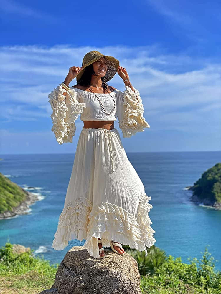 A Woman In A White Dress Standing On Top Of A Rock