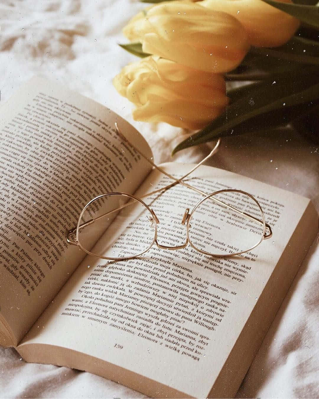 An Open Book With Glasses And Yellow Tulips