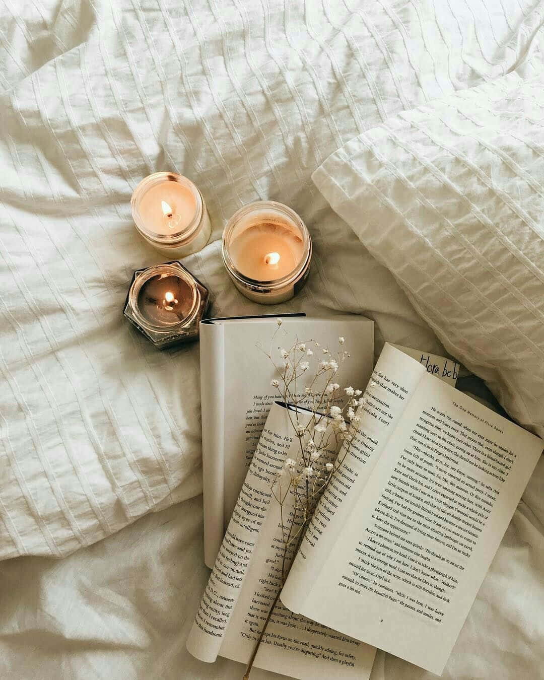 A Book, Candles, And Flowers On A Bed
