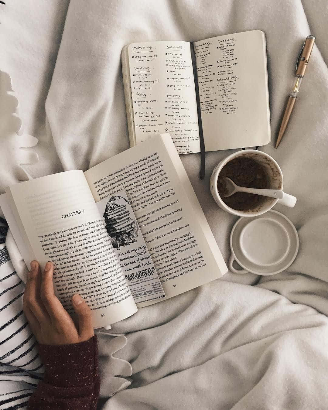 A Person Is Reading A Book On A Bed With A Cup Of Coffee