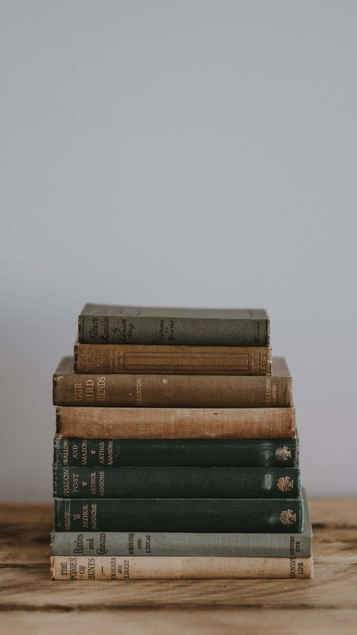 A Stack Of Books On A Wooden Table