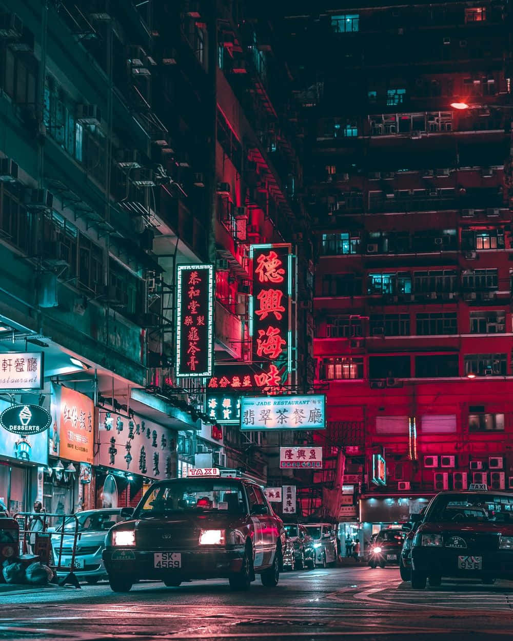 En by gade om natten med neon skilte og gade lamper Wallpaper