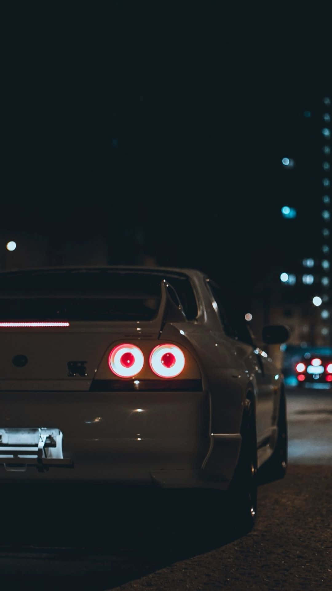 A White Car With Red Lights On The Road At Night Wallpaper
