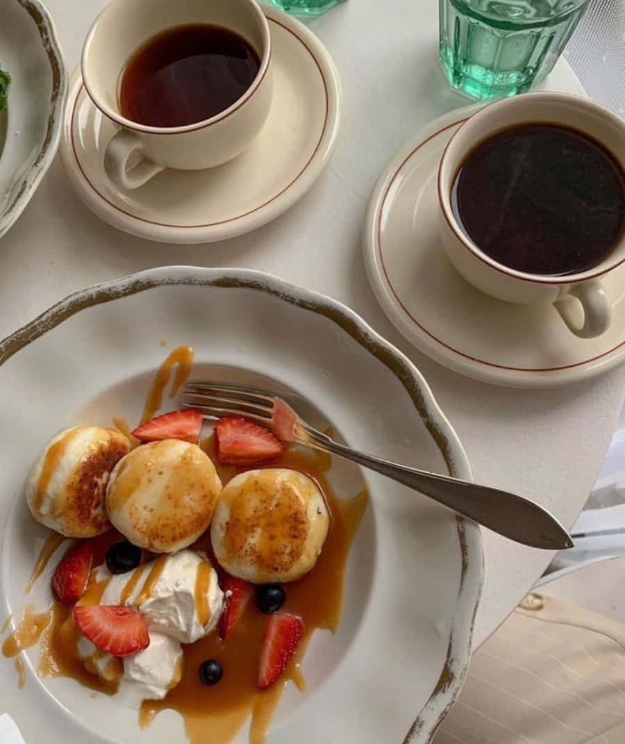 A Plate Of Pancakes With Strawberries And Coffee