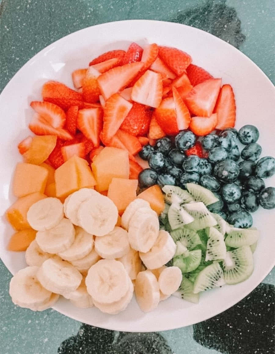 A Plate Of Fruit With Strawberries, Bananas, And Blueberries