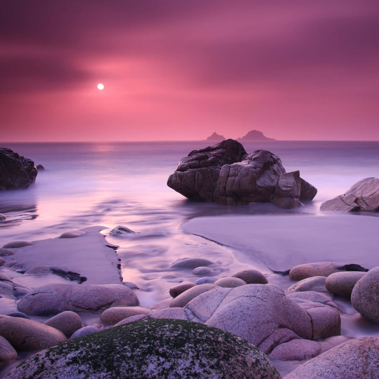 A Pink Sunset Over Rocks And Water