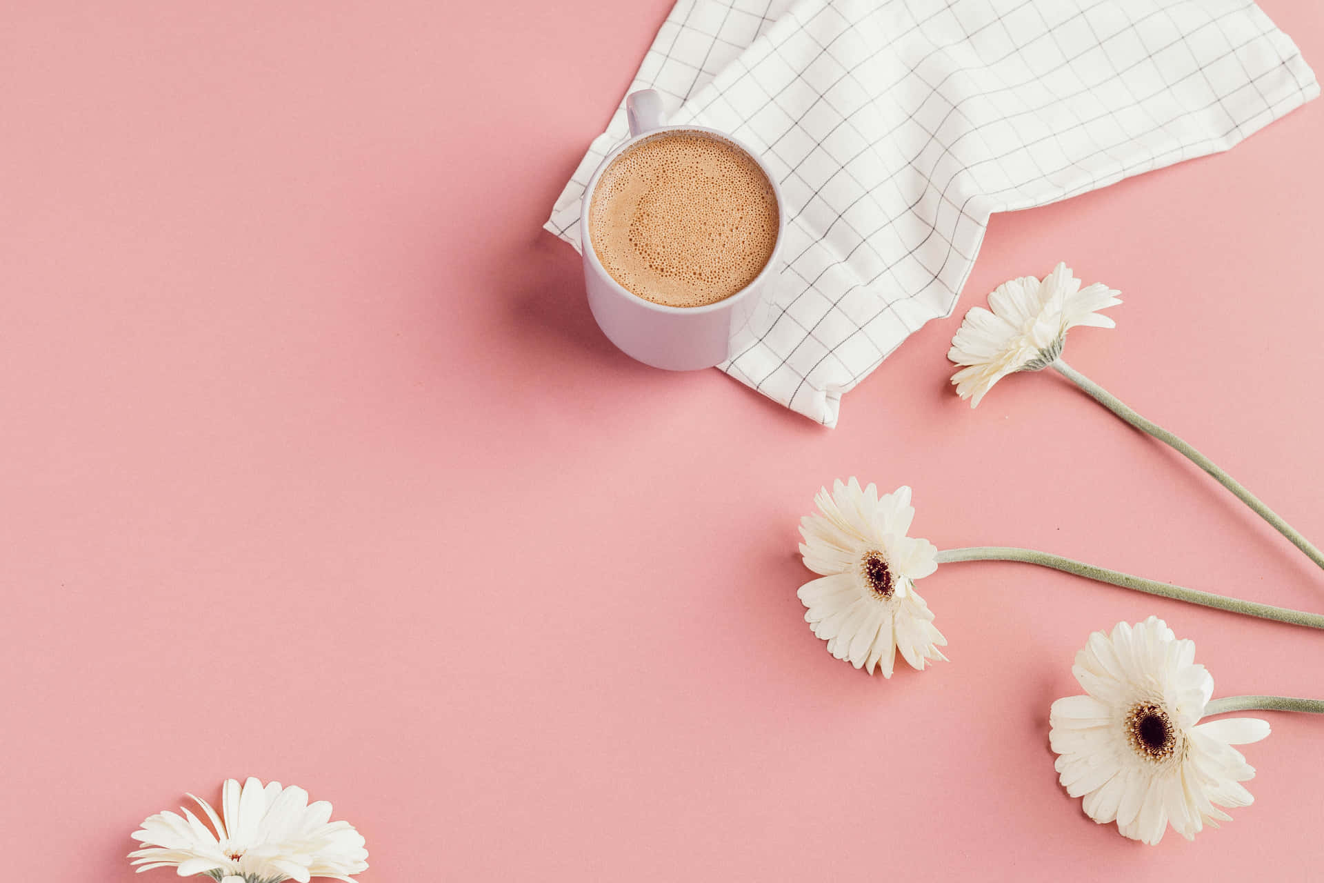 a cup of coffee and flowers on a pink background