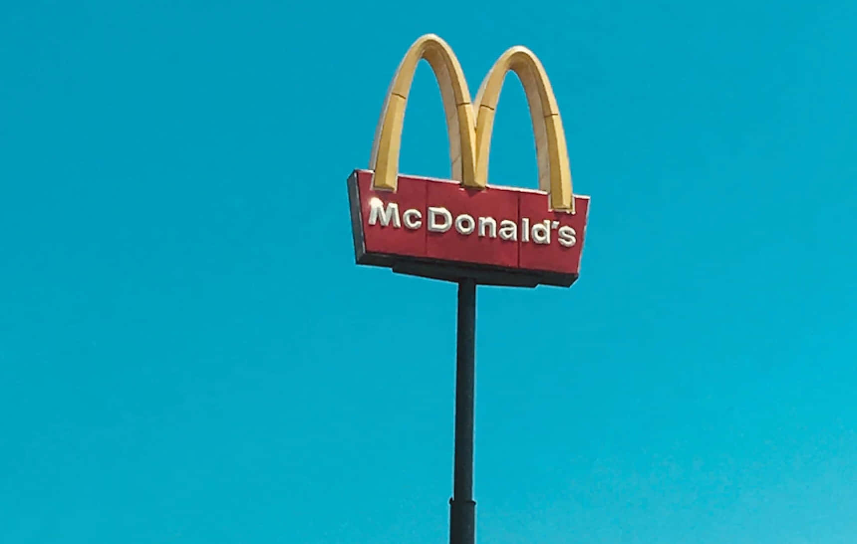 En skilt fra McDonalds med en blå himmel som baggrund. Wallpaper