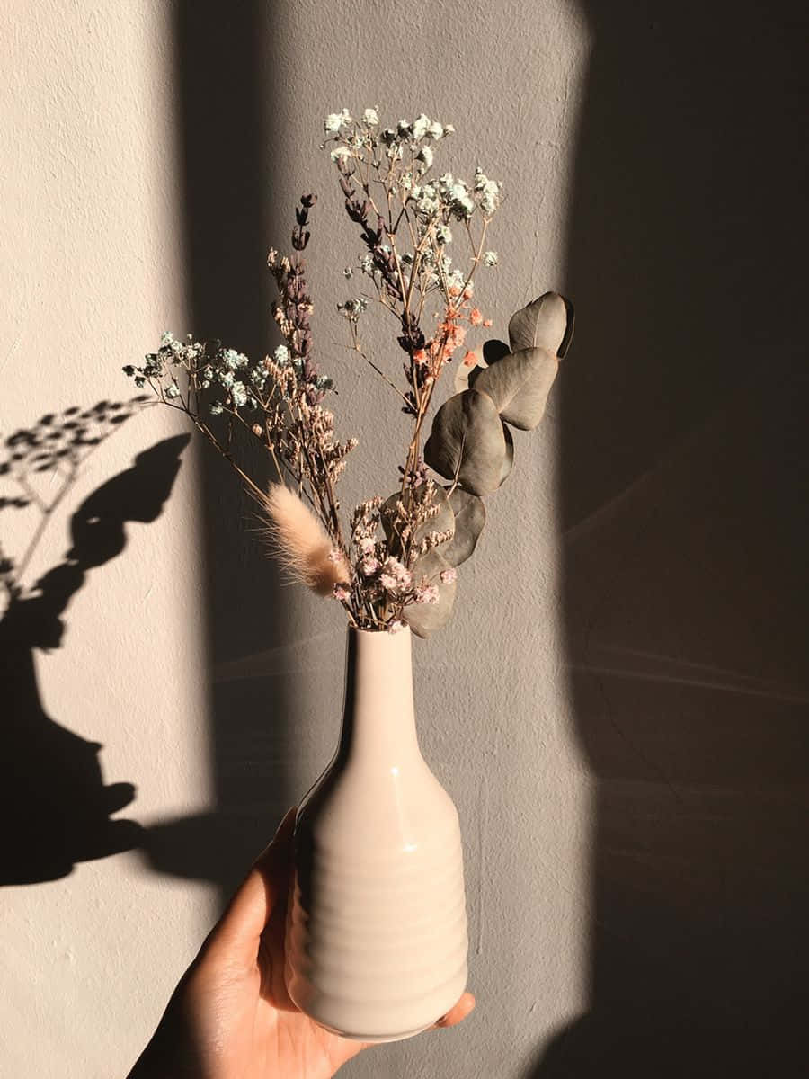 A White Vase With A Few Dried Flowers In It