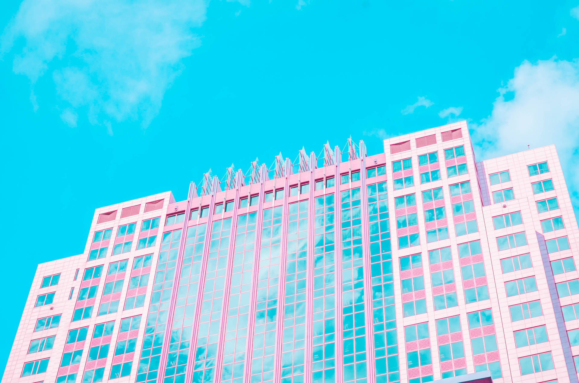 Aesthetic wallpaper of wide pink building with lots of windows reflecting blue sky