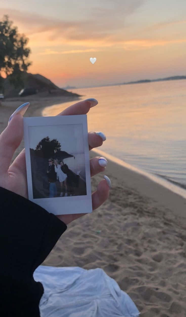A Person Holding A Photo Of A Beach At Sunset