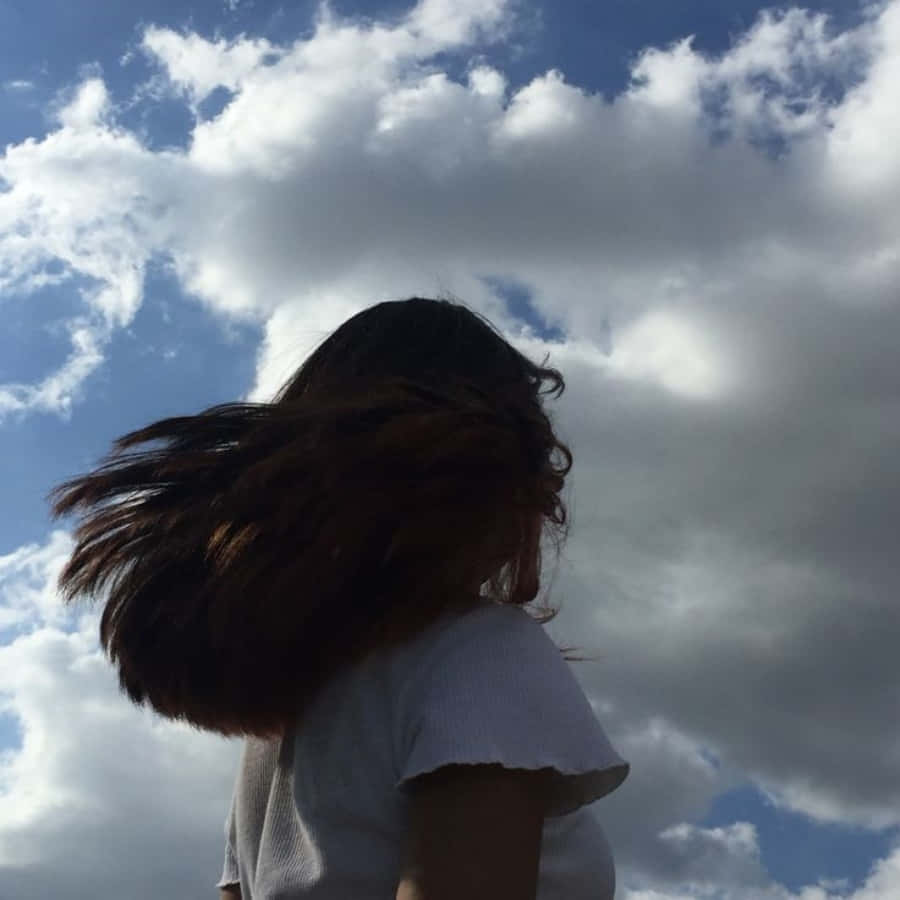 A Woman With Long Hair Standing In Front Of A Blue Sky Wallpaper