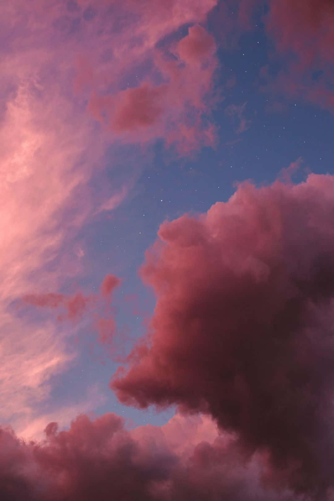 A Pink Sky With Clouds And Stars