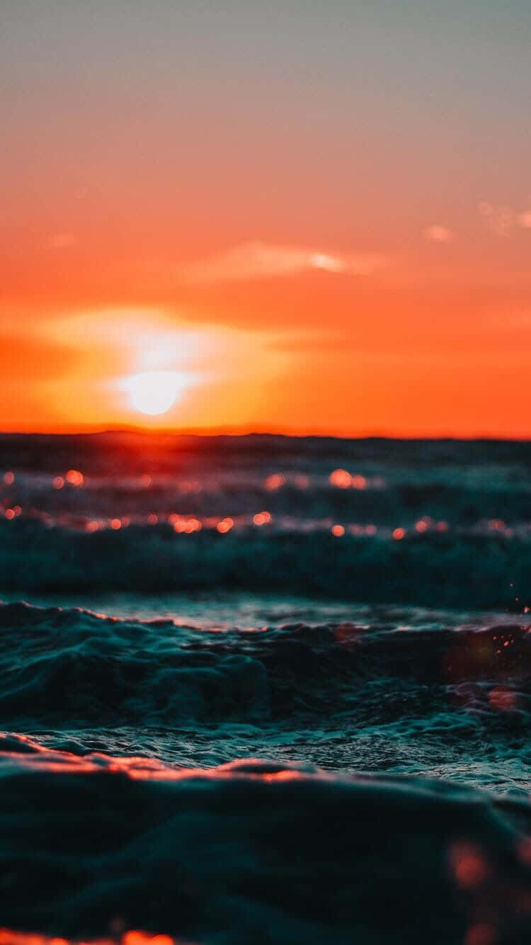 Aestetisk solnedgang iphone af solen, der reflekterer på havbølger. Wallpaper