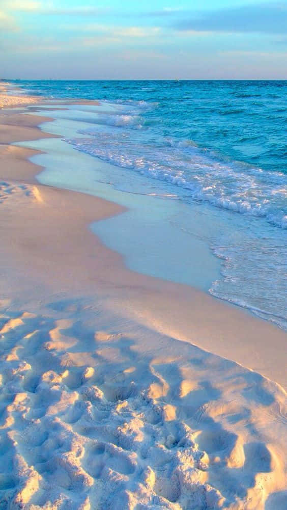 Download A Beach With White Sand And Blue Water Wallpaper | Wallpapers.com