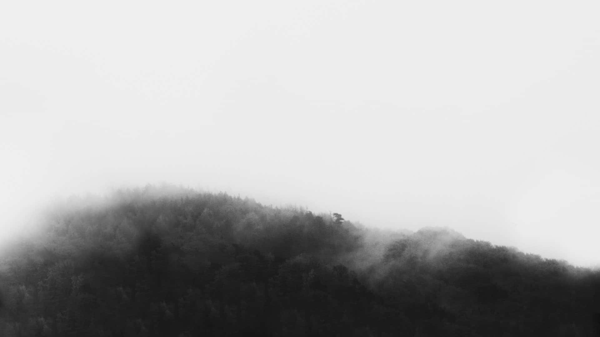 A Black And White Photo Of A Mountain Covered In Fog