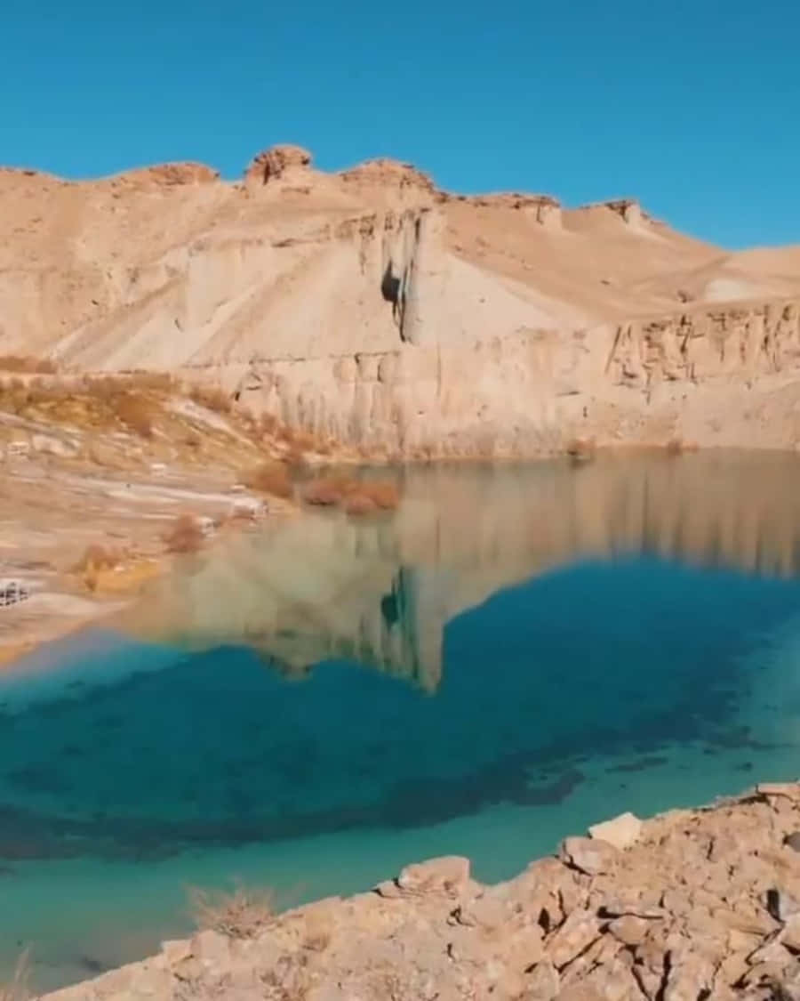 A Blue Lake In The Desert With A Rock In The Middle