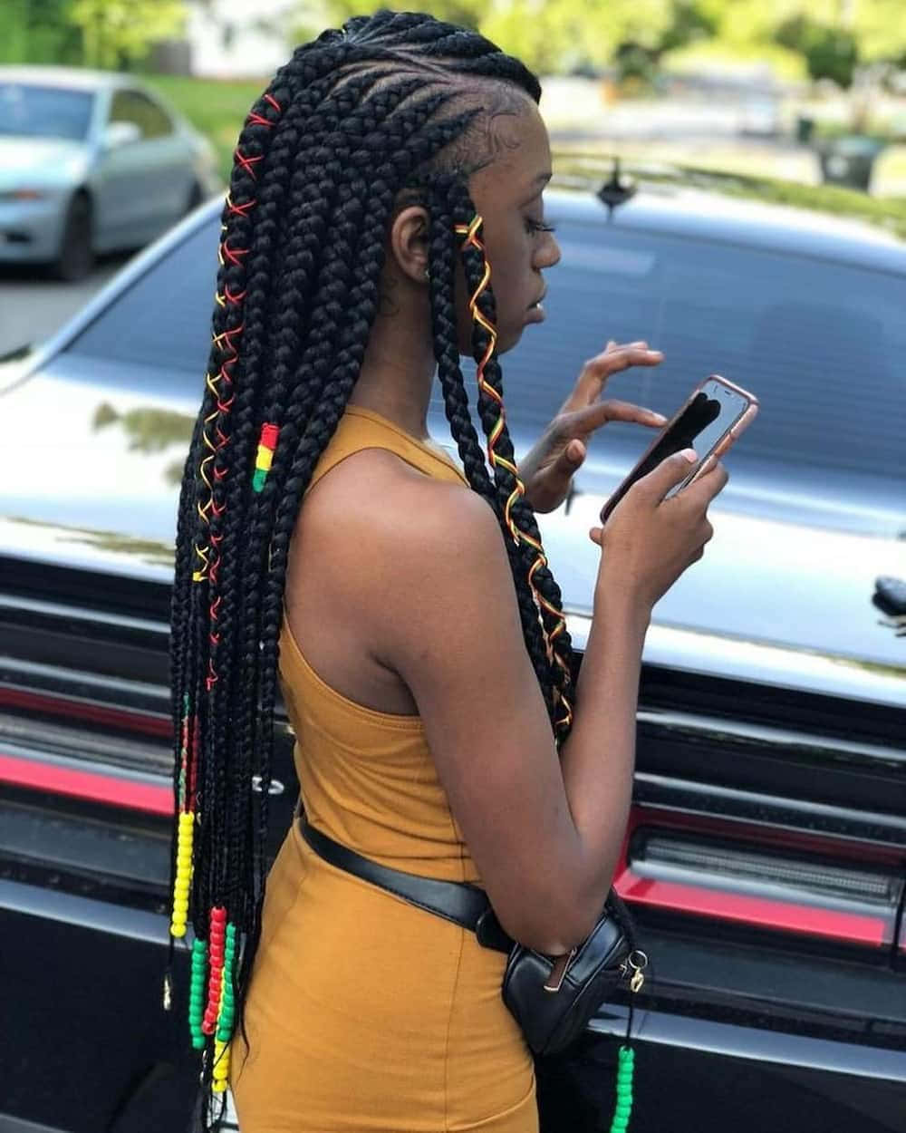 A Woman With Long Braids Is Looking At Her Phone