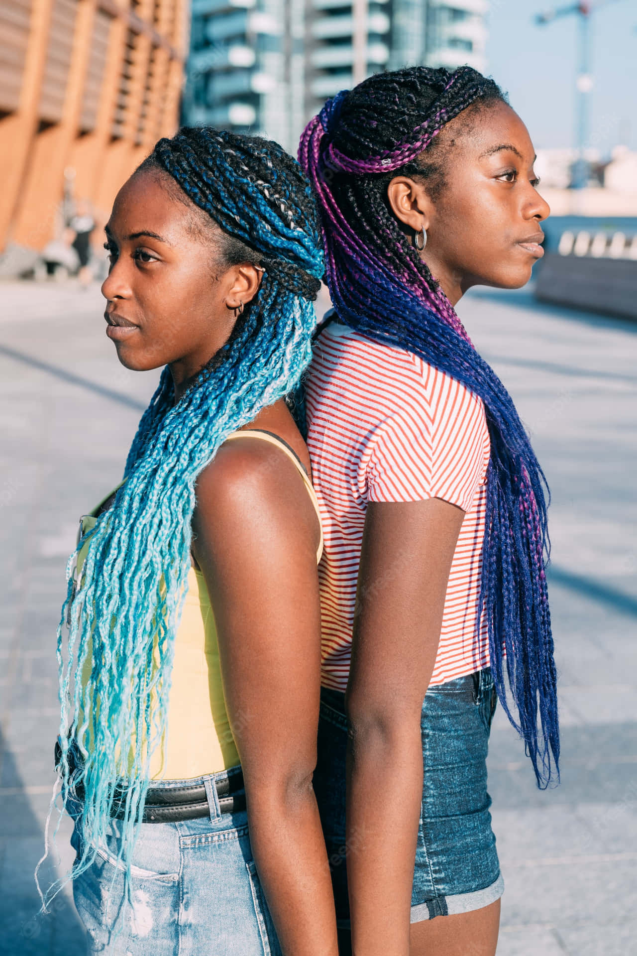 To kvinder med farverige fletninger der står ved siden af hinanden