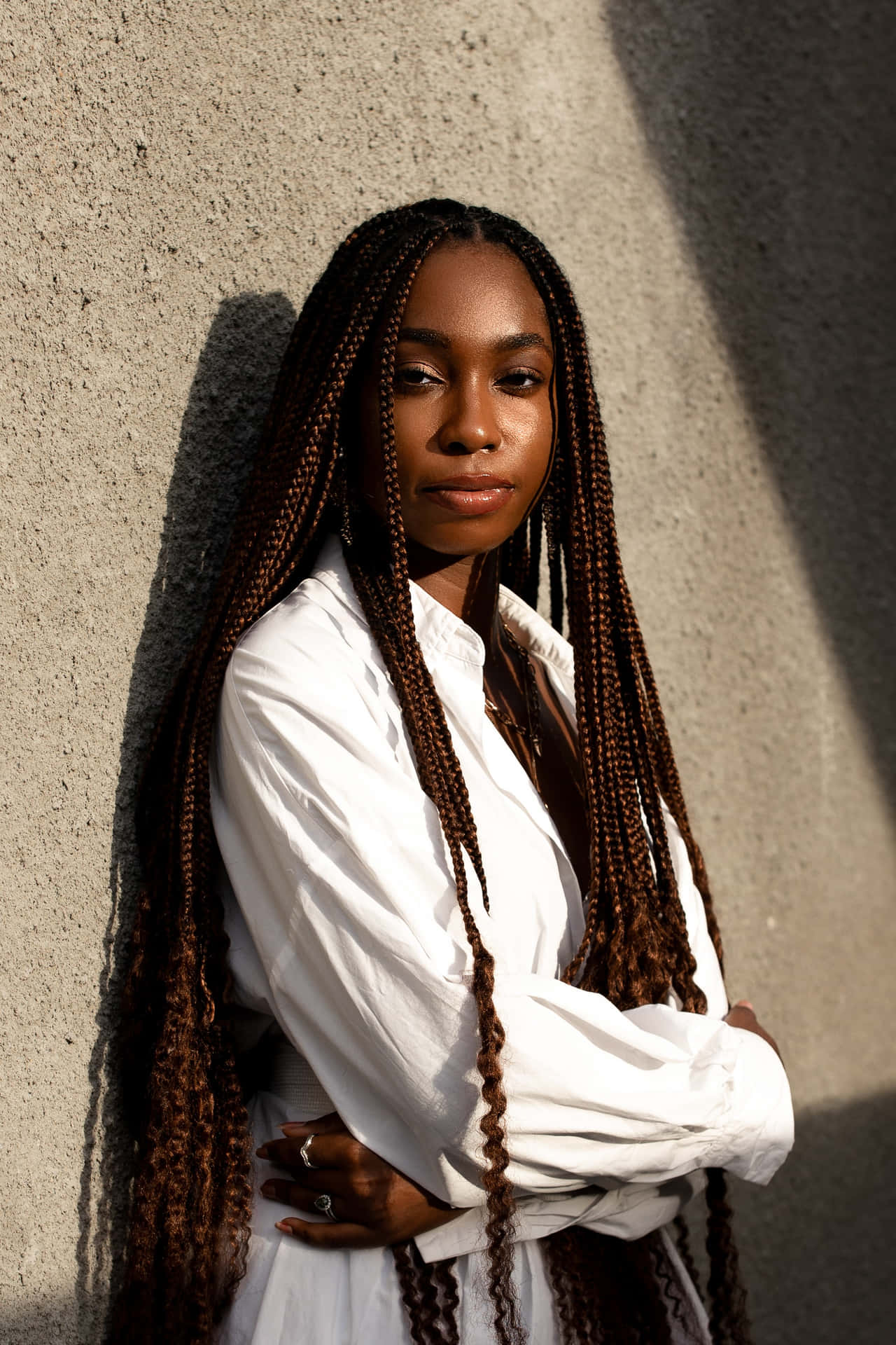 A Young Woman With Long Dreadlocks Leaning Against A Wall