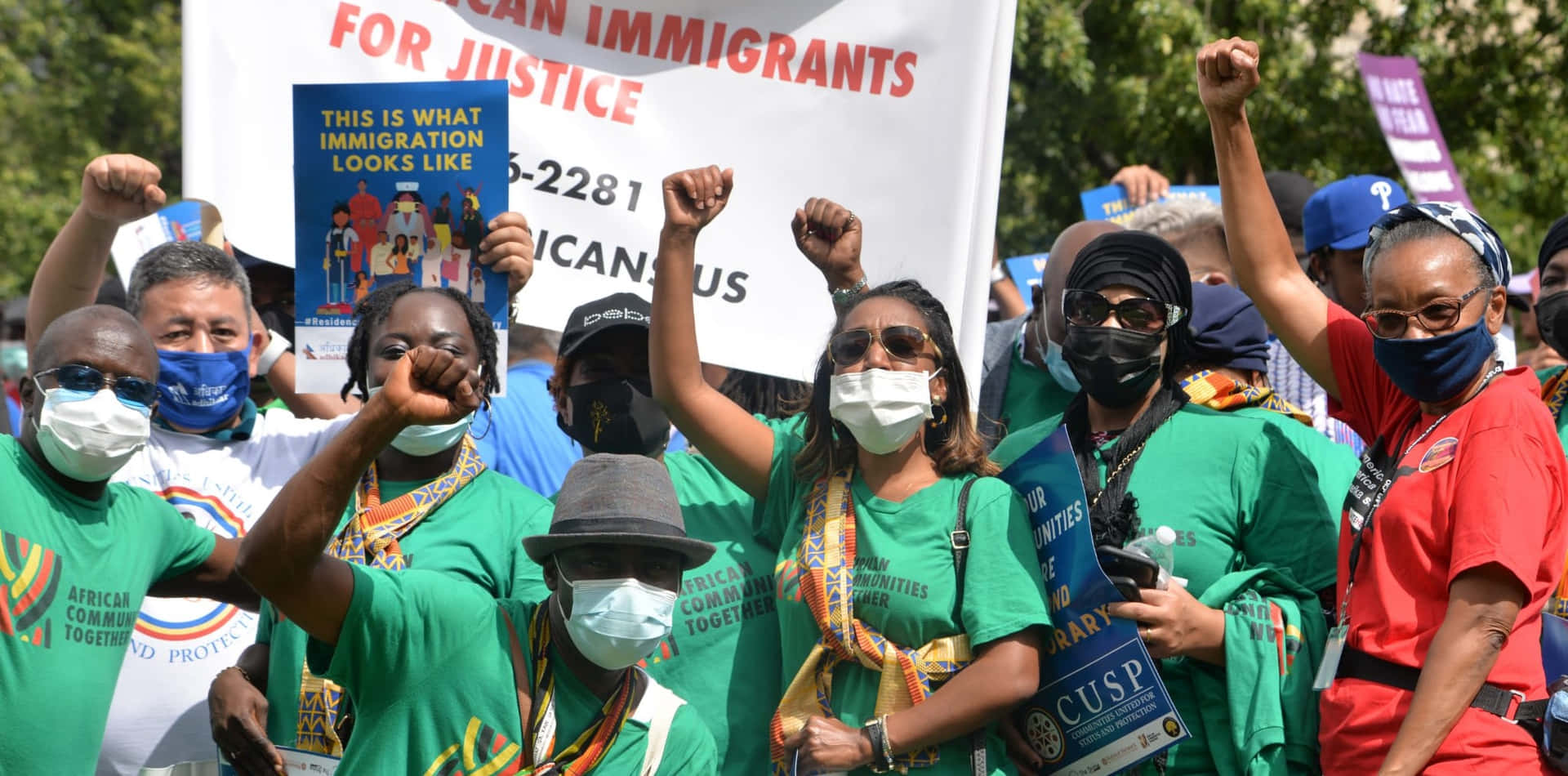 A Group Of People Holding Signs And Wearing Masks