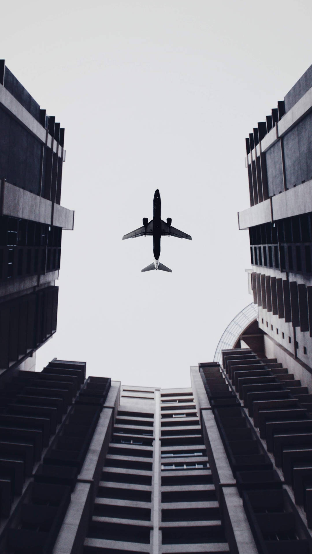 Airplane Above Buildings 2160x3840 Wallpaper