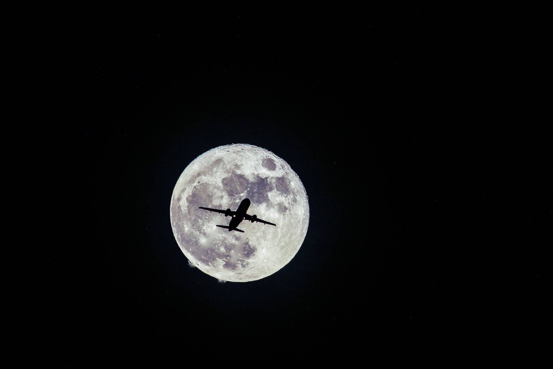 A silhouetted airplane soaring against a nocturnal starry sky Wallpaper