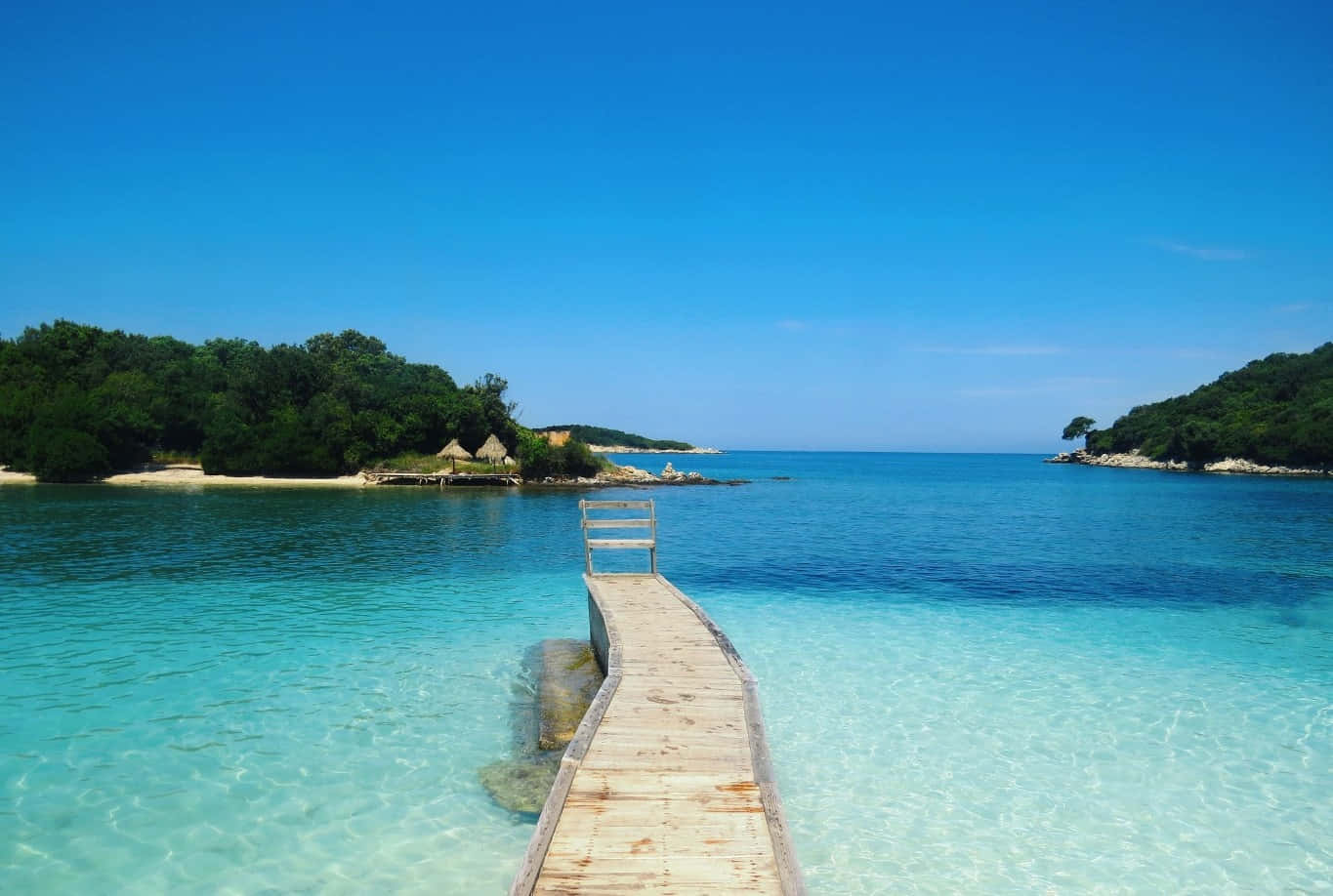 A Wooden Pier Leading To A Clear Blue Water