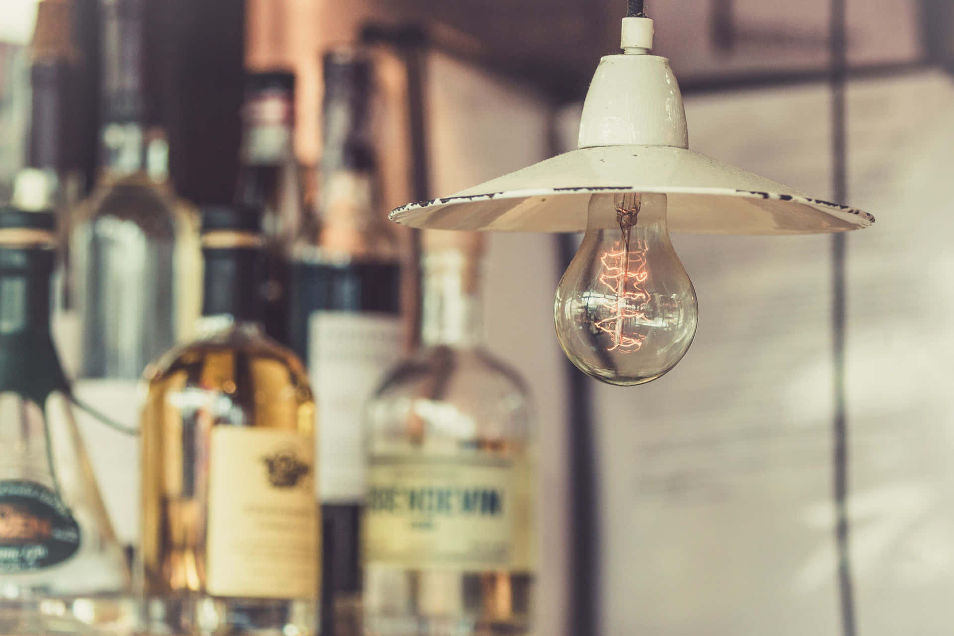 A Light Bulb Hanging Over A Bar With Bottles Of Liquor