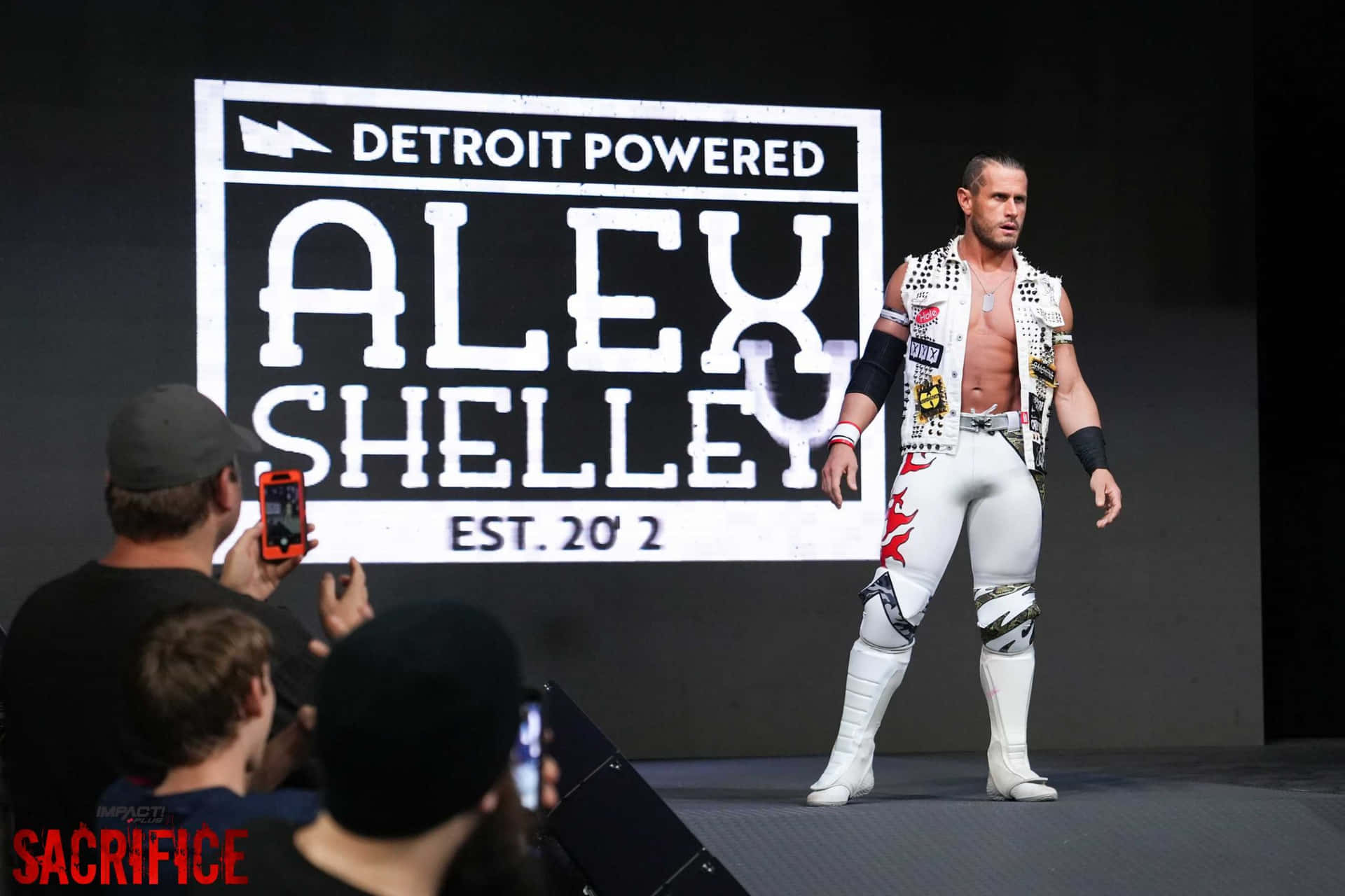 Alexshelley Posando Con Un Póster De Detroit Powered. Fondo de pantalla