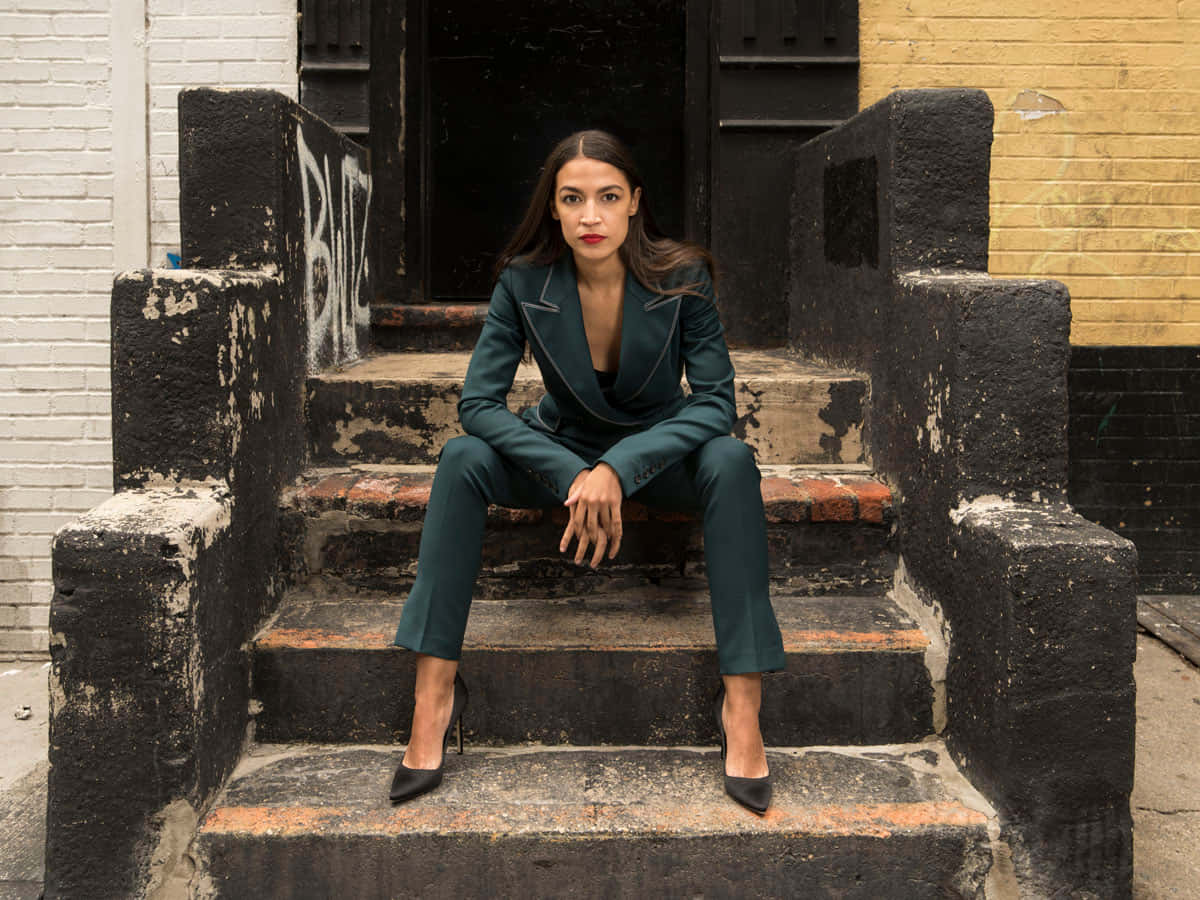 Alexandria Ocasio-cortez Sitting On The Steps Wallpaper