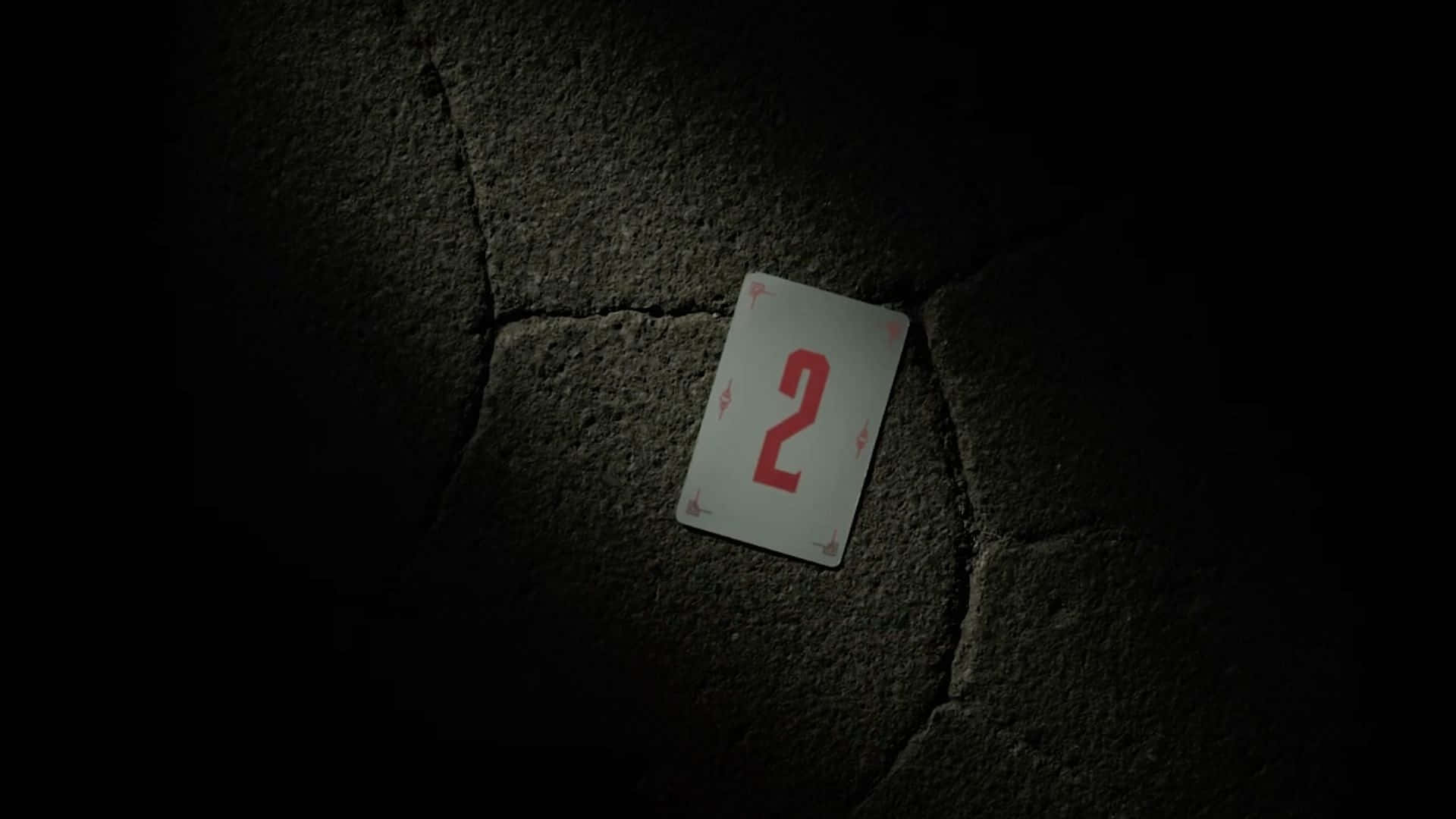 A Playing Card Is Sitting On A Dark Concrete Wall