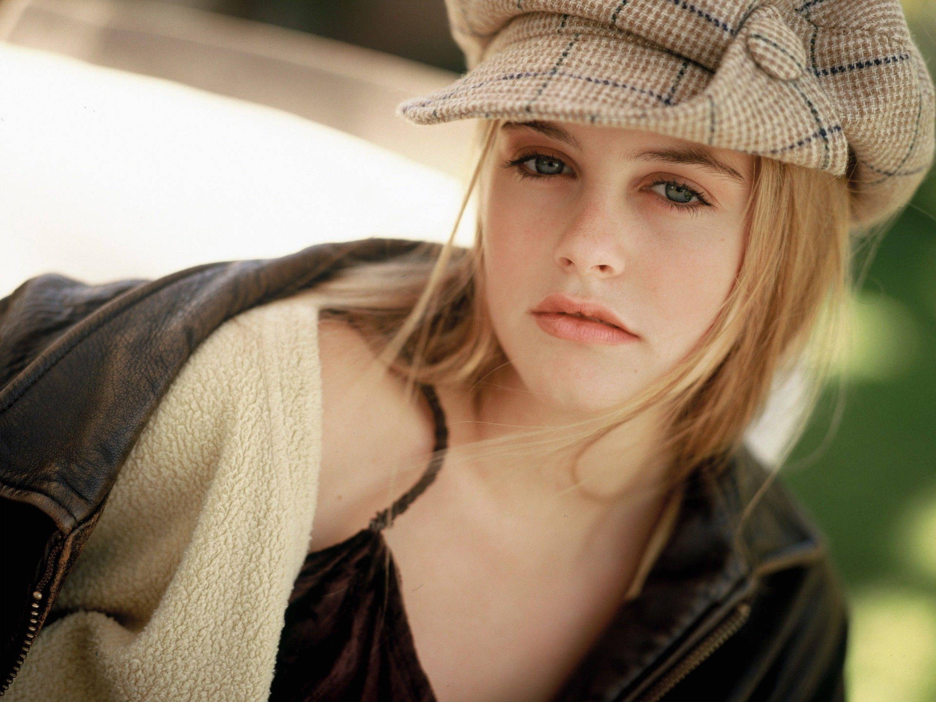 Alicia Silverstone donning a classic brown plaid cap Wallpaper