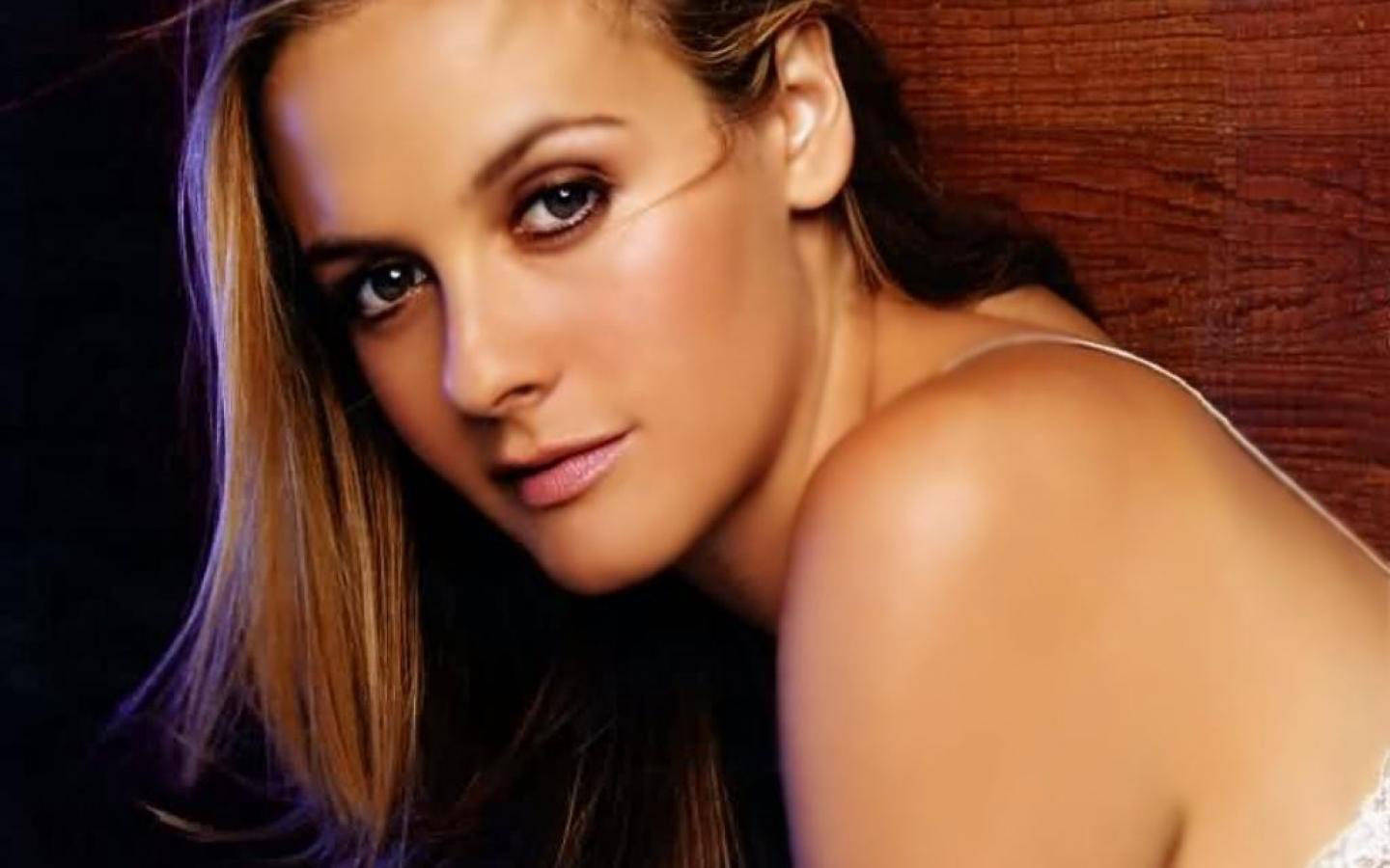 Alicia Silverstone Poses Against a Wooden Background Wallpaper