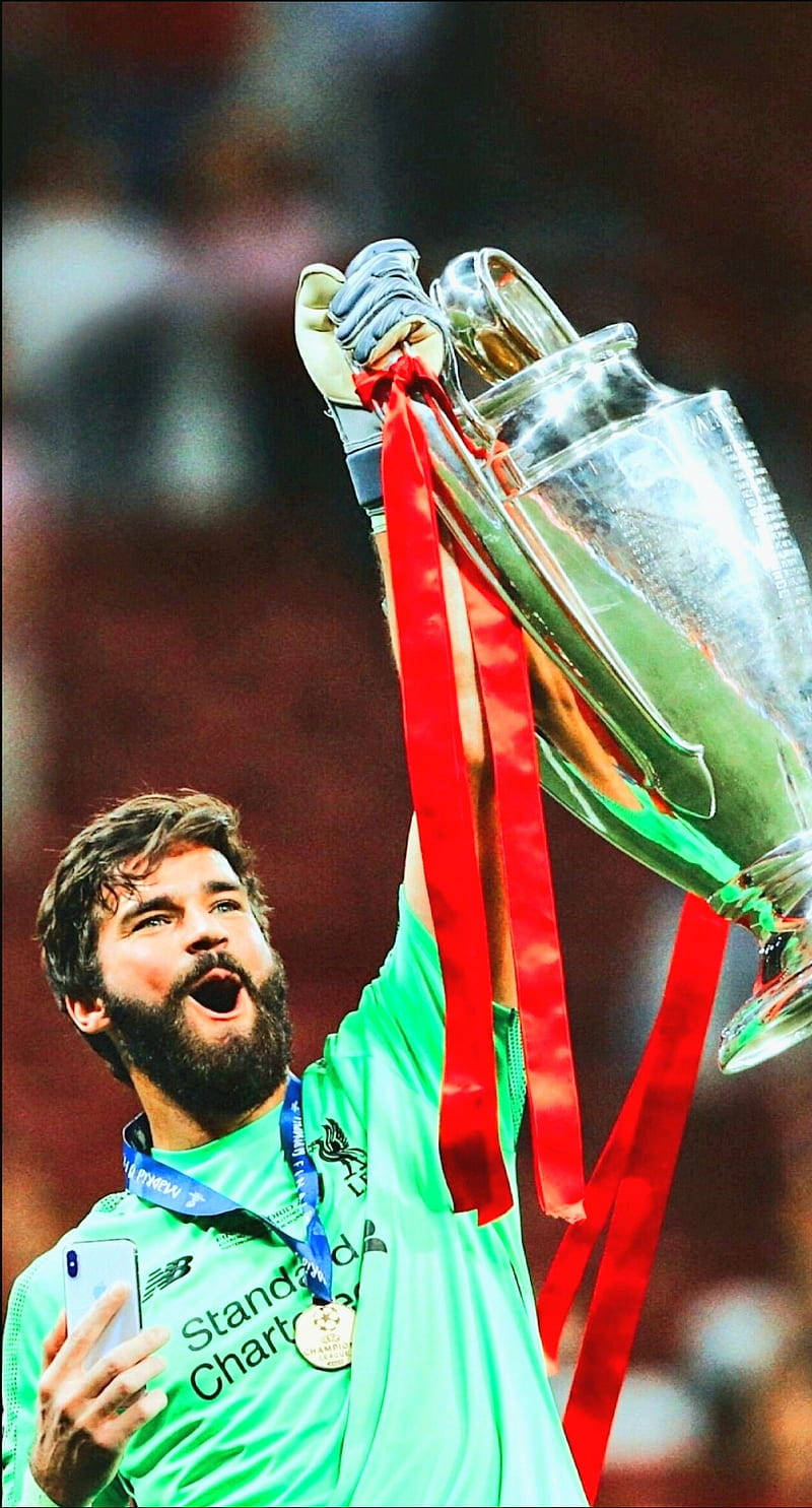Alisson Becker Holding a Trophy and Medal in Triumph Wallpaper