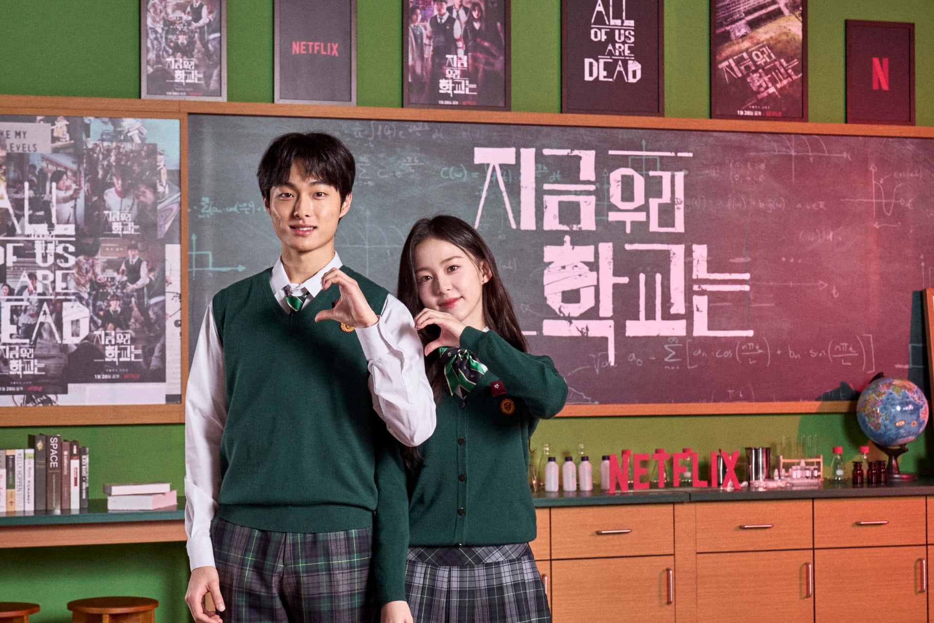A Couple In School Uniforms Standing In Front Of A Chalkboard