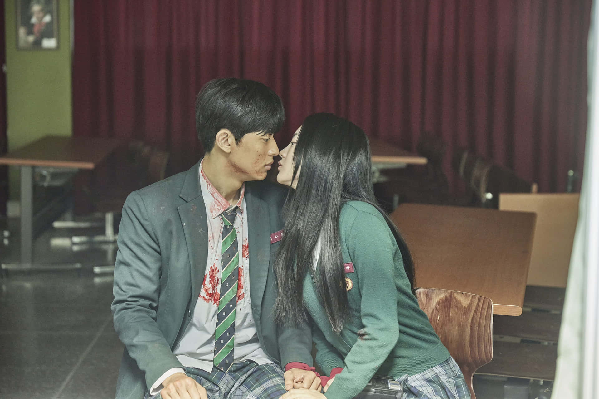 A Young Couple Kissing In A School Room