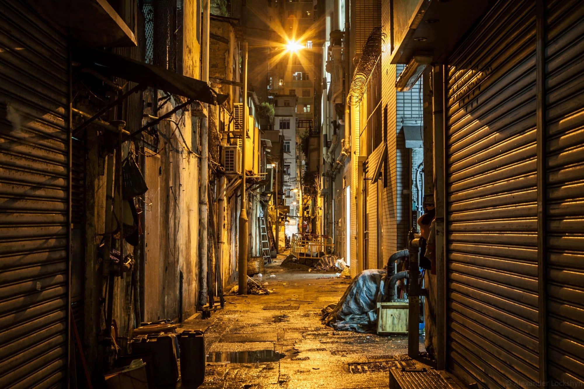 A Dark Alley With A Lamp And A Trash Can