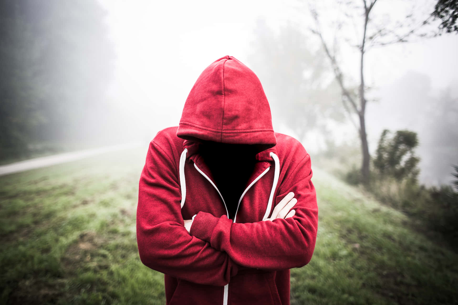 A Man In A Red Hoodie Standing In A Foggy Field