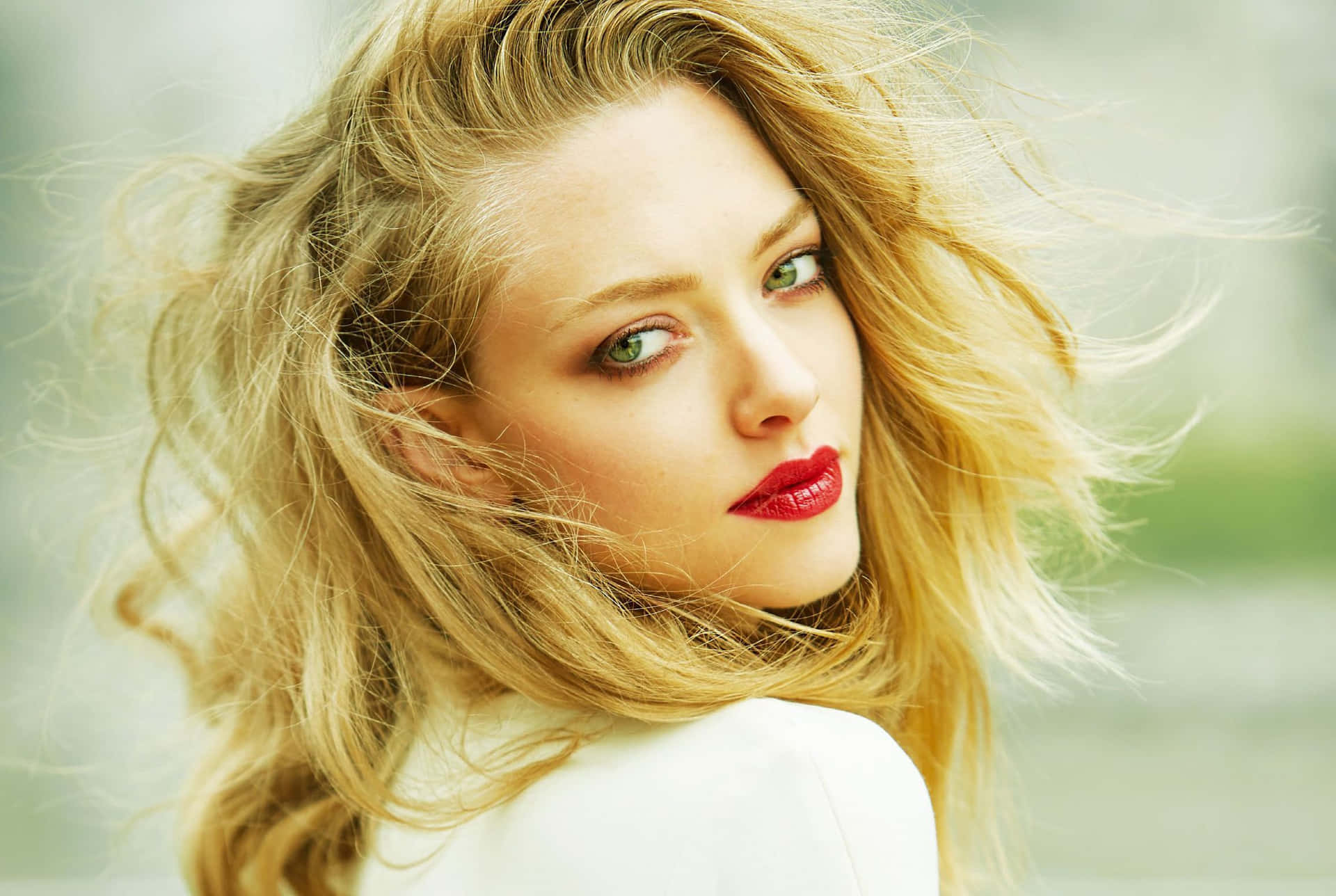 Amanda Seyfried striking a sophisticated pose with her wavy blonde hair and stunning makeup.