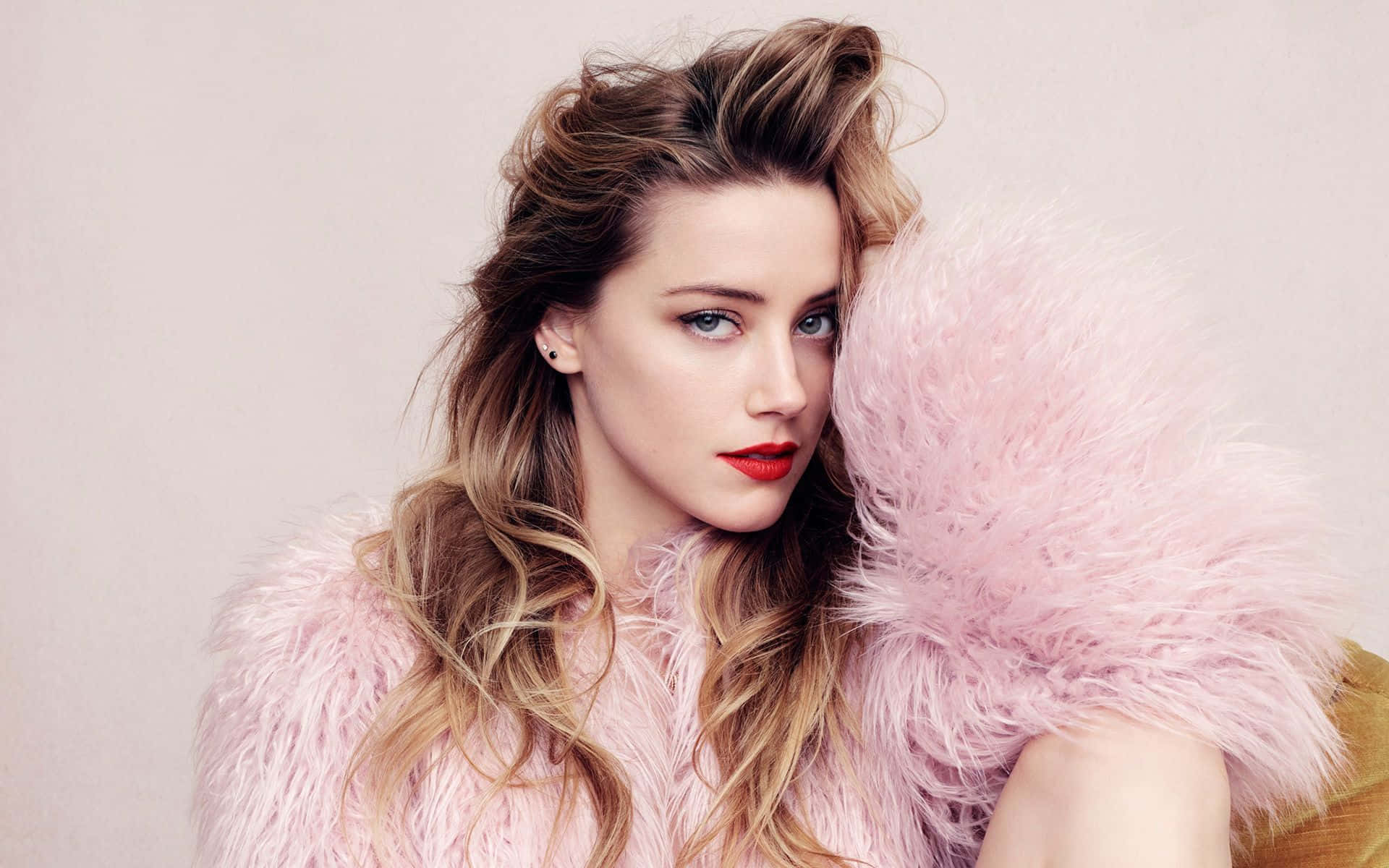 a woman in a pink fur coat posing on a couch