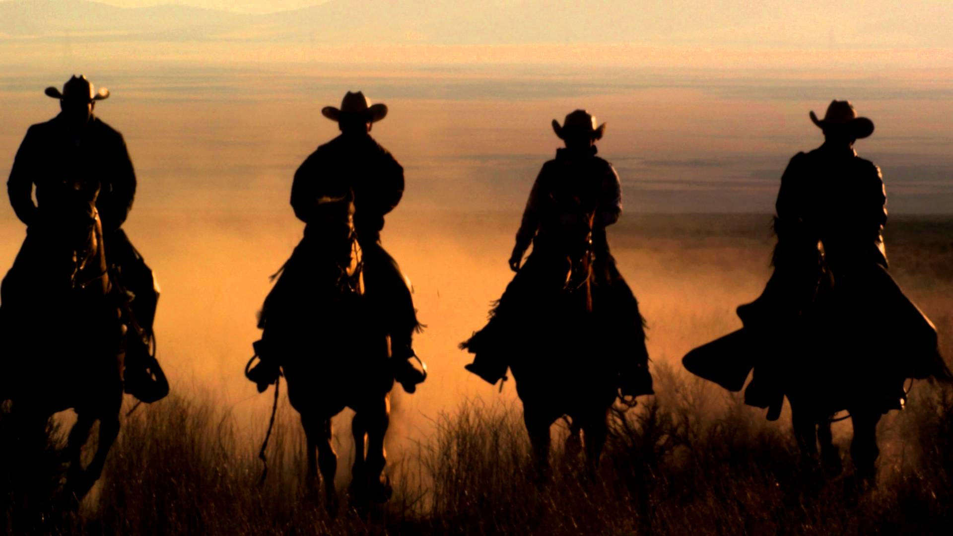 Fire cowboys som rider heste i ørkenen Wallpaper