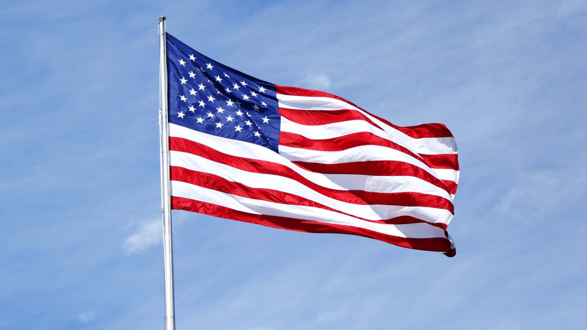 A photograph of the iconic American flag waving against a clear blue sky