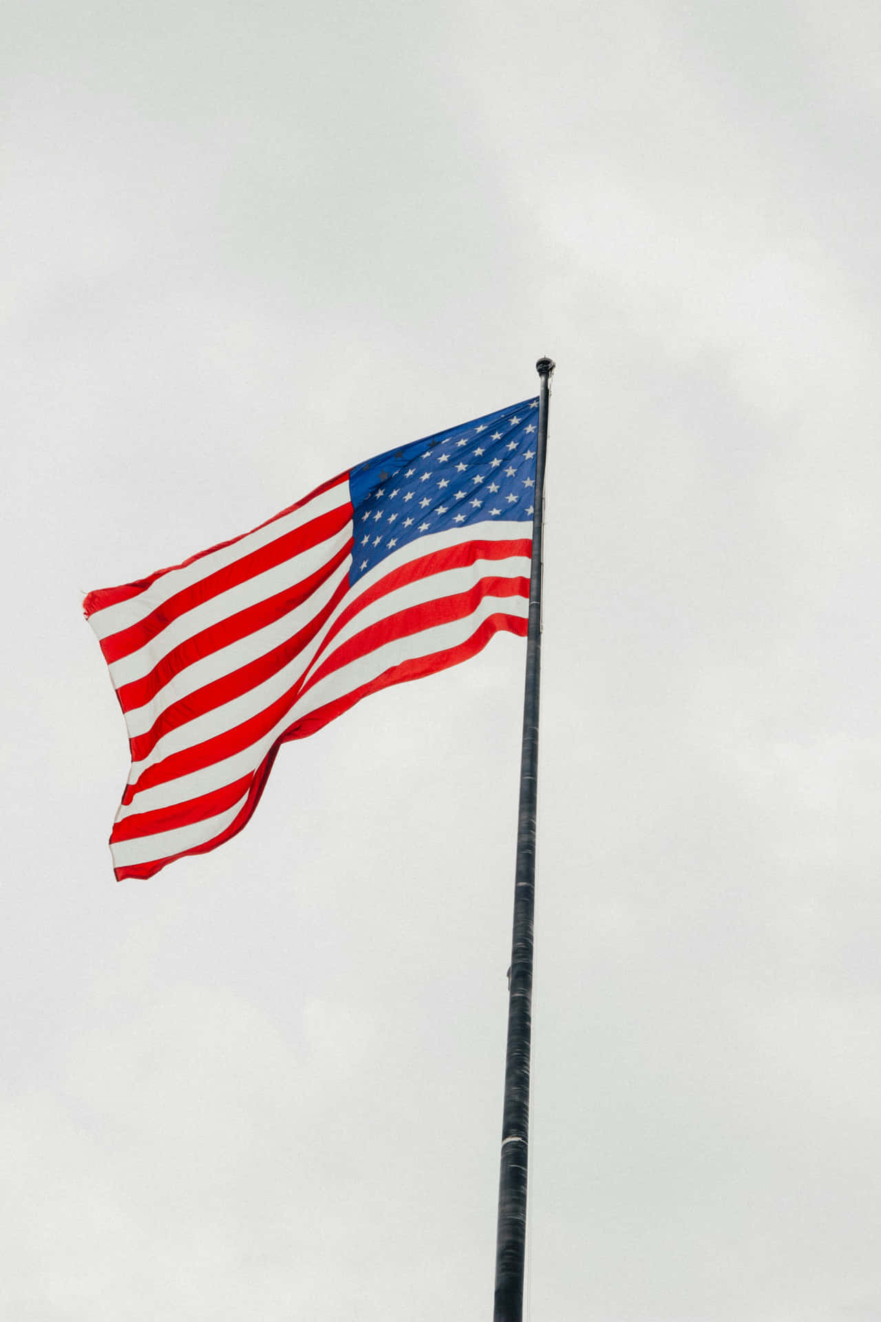 American Flag Waving Against Cloudy Sky Wallpaper