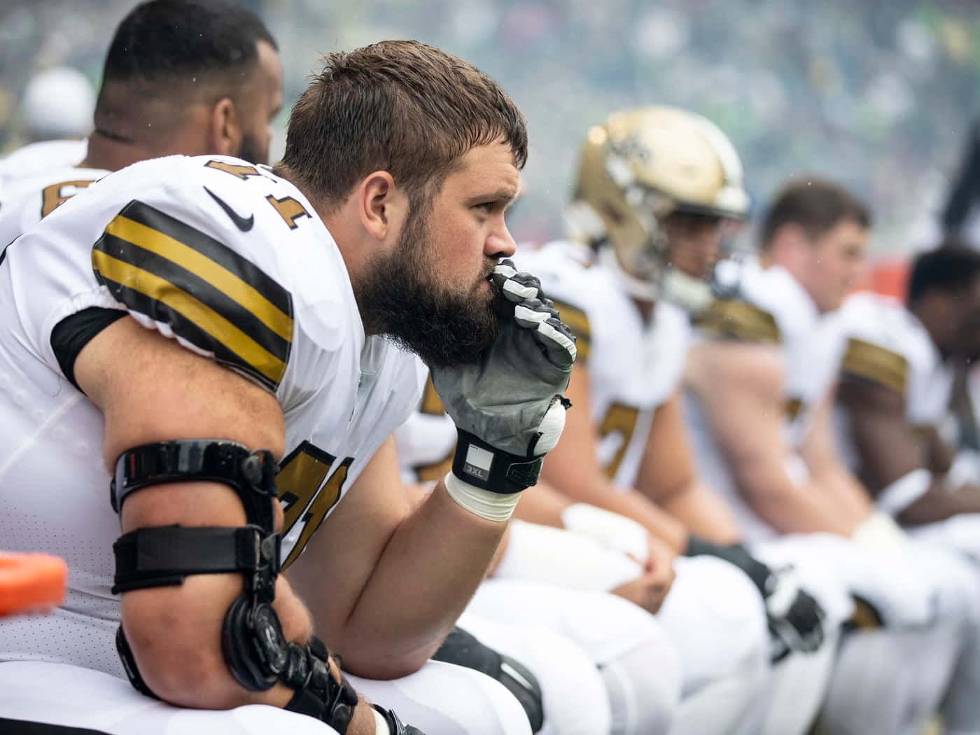 American Football Player Ryan Ramczyk Sitting And Observing On Bench Wallpaper