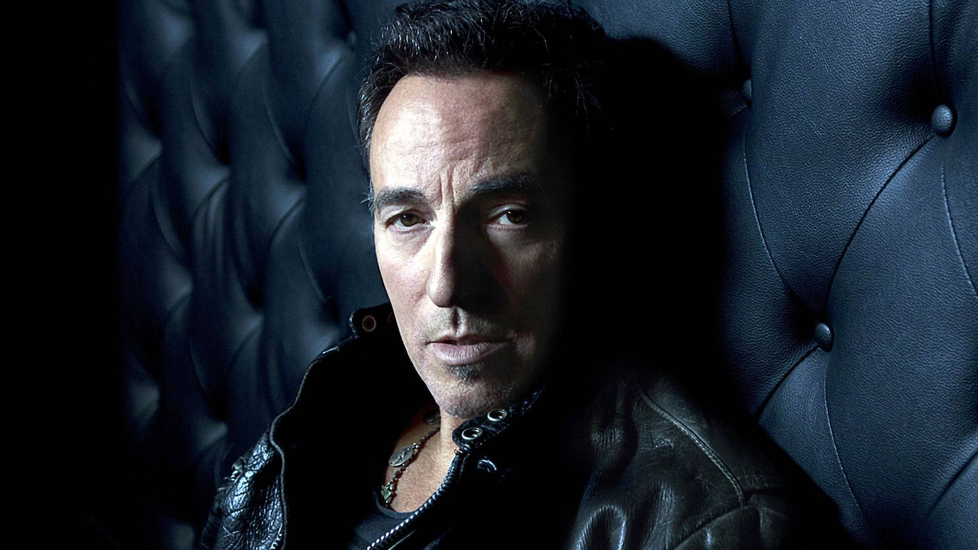 Amerikanischerrocker Bruce Springsteen Auf Schwarzem Sofa Wallpaper