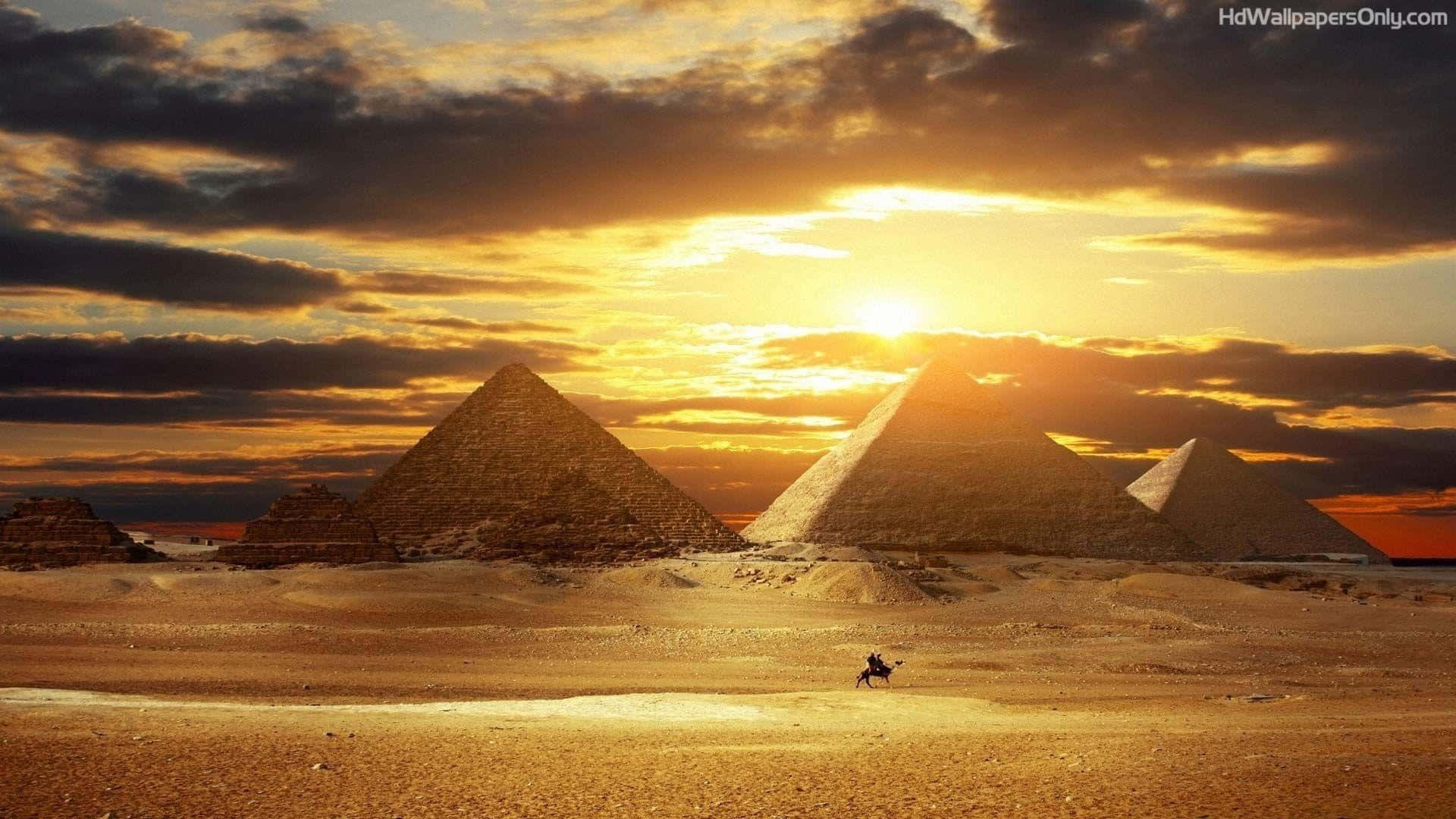 Unhombre Está Parado Frente A Las Pirámides Al Atardecer. Fondo de pantalla